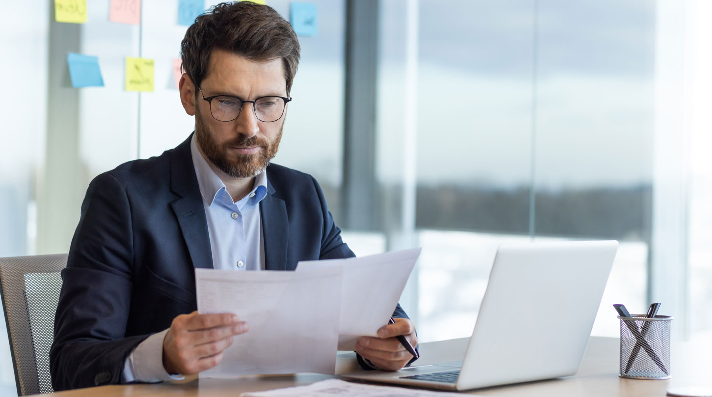 Responsable administrative d'entreprise lisant attentivement un courrier de renouvellement de contrat énergie dans son bureau professionnel